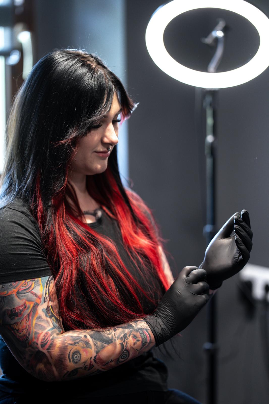 Lisa, Inhaberin und Tätowiererin des Scorpion Ink Tattoo Studios in Bautzen — beim Anziehen der Latex-Handschuhe vor einem Ringlicht.